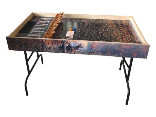 a wooden table with a decorative design on the surface, including a deer and a forest scene. There are also some small objects on the table, such as a small toy and a pack of cigarettes.