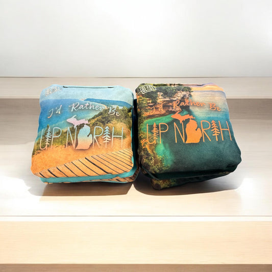 Two pillows with the text "I'D Rather Be UP NORTH" printed on them, sitting on a wooden surface.
